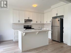 Milton (Bw Bowes) townhouse for rent - A kitchen with white cabinets and a stainless steel refrigerator.