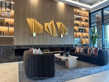 Vaughan (Vaughan Corporate Centre) condo for rent - A modern living room with a black sofa and a fireplace.