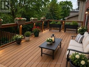 London North (North H) apartment for rent - A wooden deck with a table and chairs surrounded by greenery.