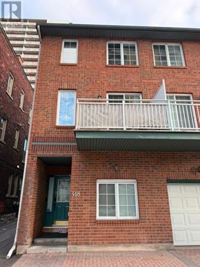 Ottawa townhouse for rent - A red brick building with a green door and a white balcony.