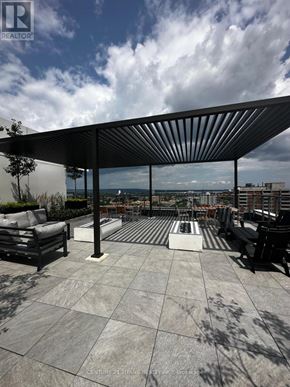 Hamilton (Beasley) condo for rent - A rooftop patio with a black metal awning and a view of the city.
