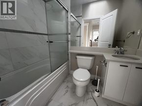 Vancouver apartment for rent - A white toilet sits in a bathroom with a marble floor and a glass shower.