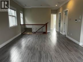 Vancouver apartment for rent - A spacious room with a wooden floor and a staircase with a metal railing.