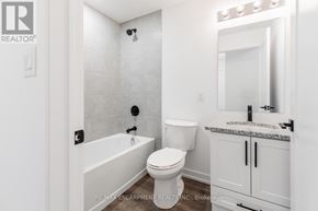 Hamilton (Waterdown) condo for rent - A white bathroom with a tub, toilet and sink.