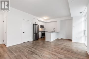 Hamilton (Waterdown) condo for rent - A spacious kitchen with white cabinets and a wooden floor.
