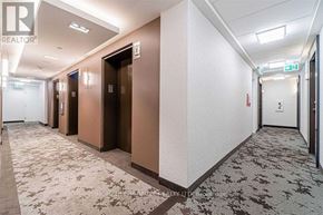 Toronto (Mimico) condo for rent - A hallway with doors on the left and a green exit sign above the door on the right.