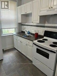 Hamilton (Stipley) triplex for rent - A kitchen with white cabinets and a black stove top.