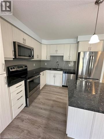 Kitchener townhouse for rent - A kitchen with a black countertop and stainless steel appliances.