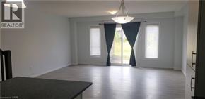 Kitchener townhouse for rent - A large empty room with a table and a window with curtains.
