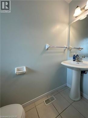 Kitchener townhouse for rent - A white pedestal sink in a bathroom with a toilet and a mirror.
