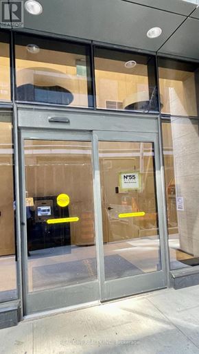 Toronto (Waterfront Communities) condo for rent - The entrance to a building with a glass door and a yellow sign on it.
