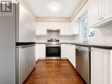 Markham (Berczy) townhouse for rent - A kitchen with white cabinets and a wooden floor.