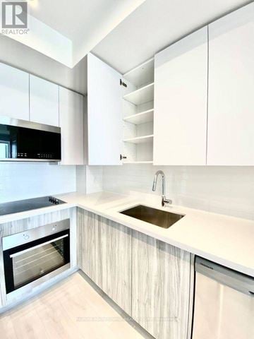 Oakville (Ro River Oaks) condo for rent - A modern kitchen with white cabinets and a wooden floor.