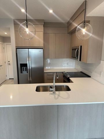 Calgary apartment for rent - A modern kitchen with a stainless steel refrigerator and a sink.
