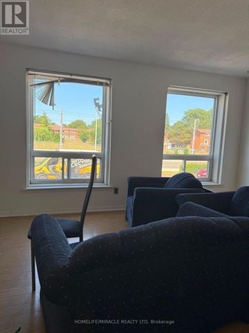 Toronto (Mount Olive-Silverstone-Jamestown) townhouse for rent - A living room with two couches and a chair in front of two windows.