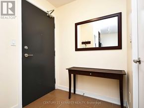 Mississauga (City Centre) condo for rent - A black door with a silver handle is on the left and a wooden table with a mirror above it is on the right.