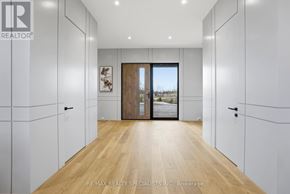Amaranth apartment for rent - A hallway with white walls and wooden floors leads to a door with a view outside.