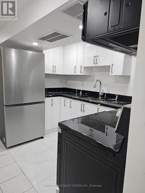 Toronto (Blake-Jones) apartment for rent - A modern kitchen with a stainless steel refrigerator and black countertops.