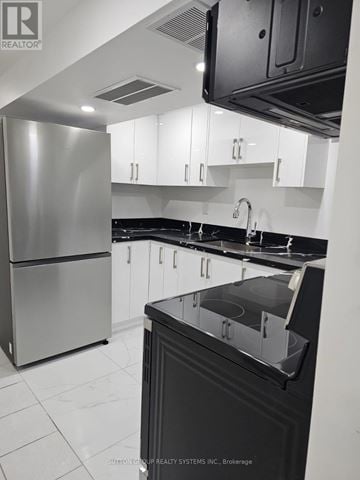 Toronto (Blake-Jones) apartment for rent - A modern kitchen with a stainless steel refrigerator and black countertops.