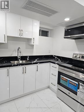 Toronto (Blake-Jones) apartment for rent - A modern kitchen with white cabinets and black countertops.