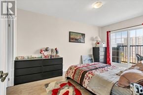 Hamilton (Corktown) condo for rent - A bedroom with a bed, dresser, and window with red curtains.