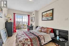 Hamilton (Corktown) condo for rent - A bedroom with a large bed and a balcony with red curtains.