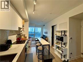 Toronto condo for rent - A well-lit kitchen with a bar area and a view of the city.