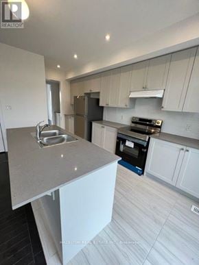 Whitby (Port Whitby) townhouse for rent - A modern kitchen with white cabinets and a marble countertop.