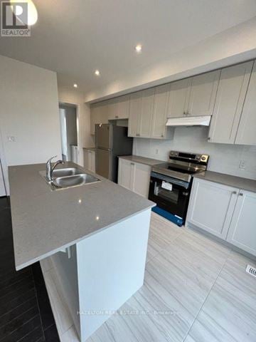 Whitby (Port Whitby) townhouse for rent - A modern kitchen with white cabinets and a marble countertop.