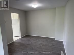 Welland (N. Welland) townhouse for rent - A room with a grey floor and white walls, with a door on the left and a light on the ceiling.