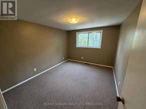 Welland (N. Welland) townhouse for rent - A room with a carpeted floor and a window with a view of trees.