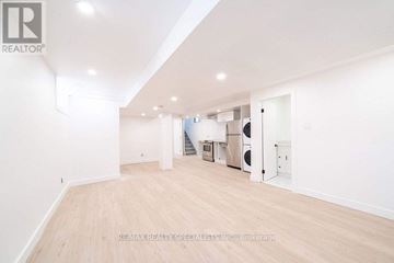 Toronto (Corso Italia-Davenport) apartment for rent - A spacious room with wooden flooring and white walls, furnished with a kitchenette.