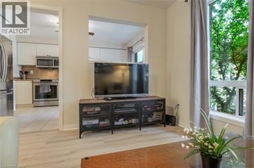 Milton townhouse for rent - A modern living room with a television and a kitchen area in the background.