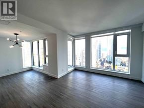 Burnaby apartment for rent - A large empty room with wooden floors and a chandelier.