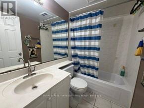 Toronto (Willowdale West) condo for rent - A bathroom with a white sink, toilet, and bathtub with a blue and white striped shower curtain.