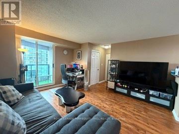 Toronto (Willowdale West) condo for rent - A living room with a grey sofa and a black chair.