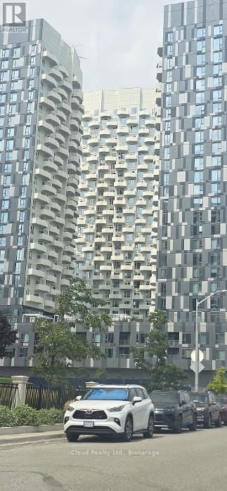 Vaughan (Concord) condo for rent - A white car is driving down a street lined with tall buildings.