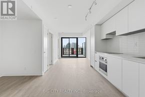 Toronto (Thorncliffe Park) condo for rent - A spacious kitchen with white cabinets and a view of the city through the glass doors.