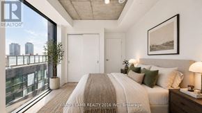 Toronto (Moss Park) condo for rent - A bedroom with a large bed and a view of the city.