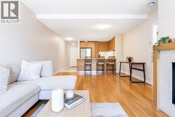 Vancouver apartment for rent - A living room with a white couch and a coffee table with a book and a candle on it.