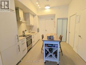 Toronto (Waterfront Communities) condo for rent - A kitchen with white appliances and a dining table with chairs.