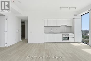 Toronto (Thorncliffe Park) condo for rent - A white kitchen with a refrigerator, cabinets, and a stove top oven.