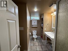 Windsor apartment for rent - A small bathroom with a toilet, sink, and mirror.