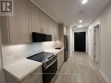Toronto (Junction Area) condo for rent - A well-lit kitchen with a stove top oven and a refrigerator.