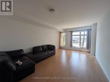 Toronto (Bendale) townhouse for rent - A living room with black leather couches and a wooden floor.