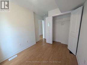 Toronto (Bendale) townhouse for rent - A room with white walls and wooden flooring, with a door on the right and a white closet with a hanger on the left.