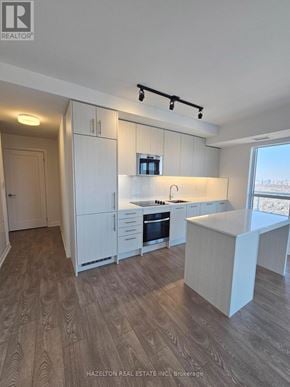Toronto (East End-Danforth) condo for rent - A modern kitchen with white cabinets and a wooden floor.