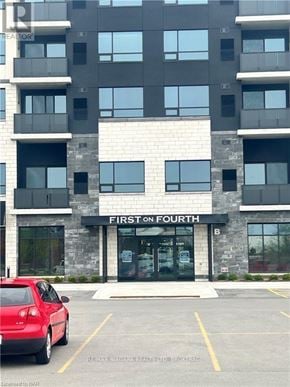 St. Catharines (Ridley) condo for rent - A red car is parked in a parking lot in front of a building called First Fourth.