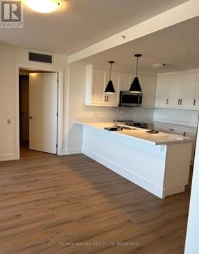 St. Catharines (Ridley) condo for rent - A white kitchen with a wooden floor and a white island in the middle.