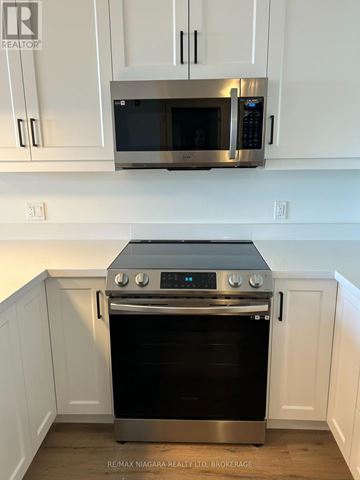 St. Catharines (Ridley) condo for rent - A stainless steel oven with a microwave above it in a kitchen.